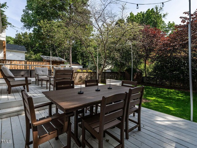wooden terrace featuring a yard, outdoor dining area, and a fenced backyard