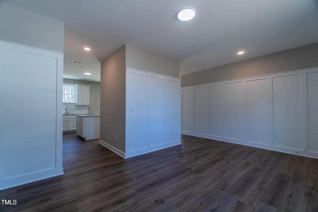 interior space with dark wood-type flooring, a decorative wall, and recessed lighting