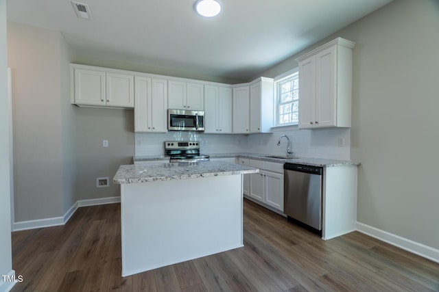 kitchen with a sink, decorative backsplash, white cabinets, appliances with stainless steel finishes, and visible vents