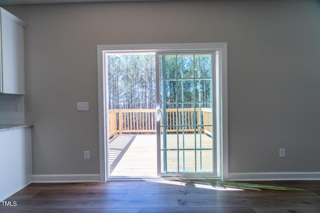 doorway with baseboards and wood finished floors