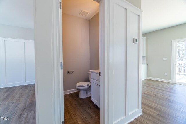 bathroom with toilet, visible vents, baseboards, wood finished floors, and vanity