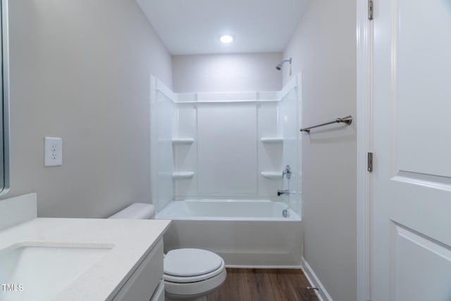 bathroom with  shower combination, toilet, baseboards, wood finished floors, and vanity