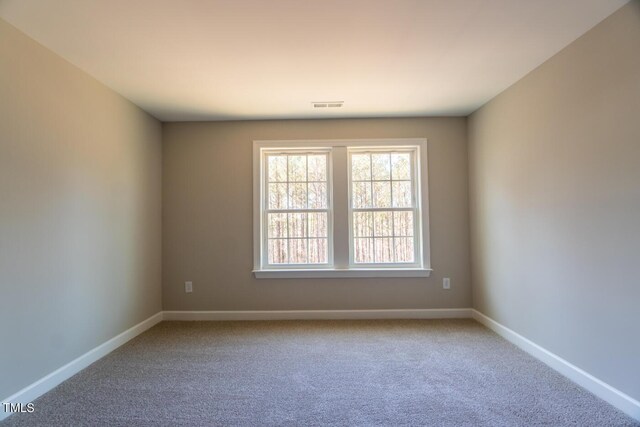 empty room with baseboards, carpet flooring, and visible vents