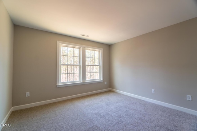 spare room featuring carpet floors, visible vents, and baseboards