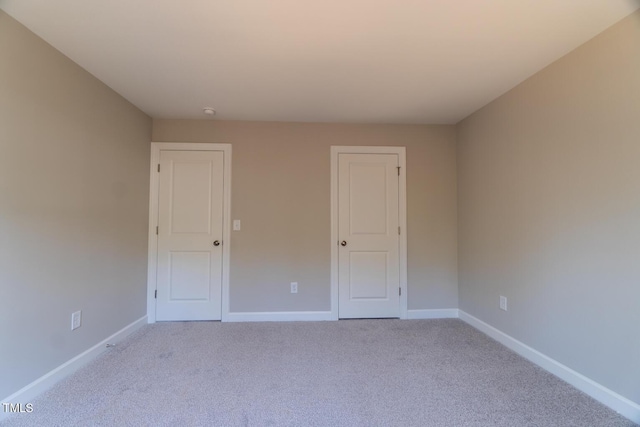 spare room featuring carpet flooring and baseboards
