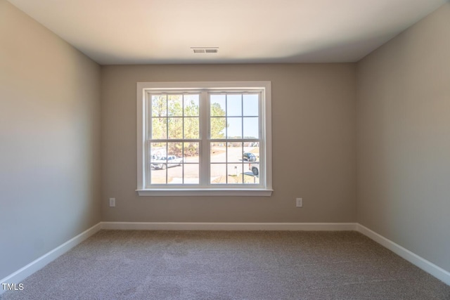 spare room featuring baseboards, visible vents, and carpet