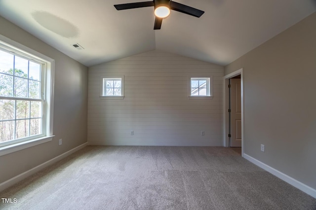 carpeted spare room with plenty of natural light, visible vents, lofted ceiling, and ceiling fan