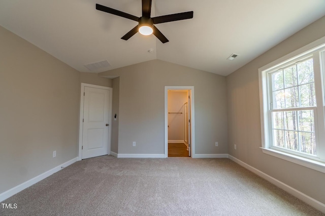 unfurnished bedroom with lofted ceiling, visible vents, carpet floors, and multiple windows