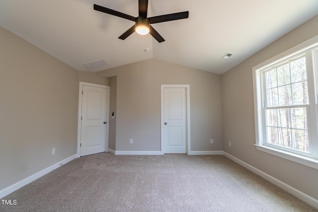 unfurnished bedroom featuring ceiling fan, baseboards, light colored carpet, lofted ceiling, and visible vents