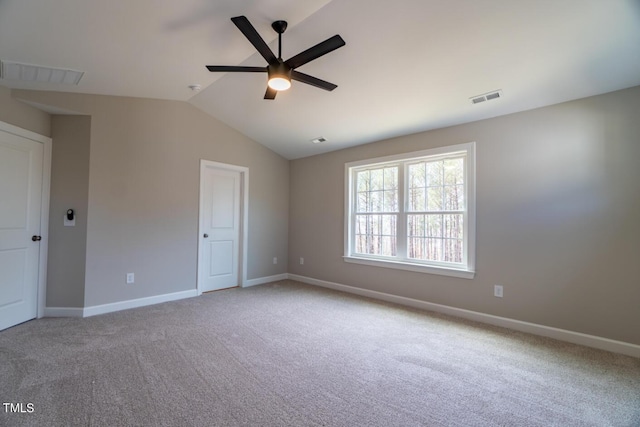 carpeted empty room featuring lofted ceiling, a ceiling fan, visible vents, and baseboards