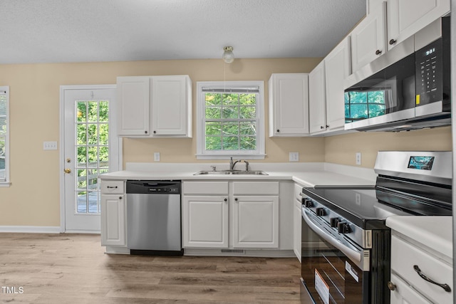 160 Fox Run Rd, Youngsville, NC 27596 - kitchen with stainless steel appliances, a sink, white cabinetry, light wood finished floors, and light countertops