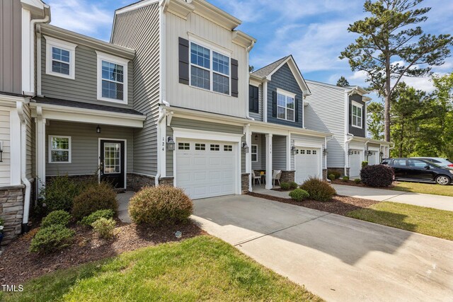 view of property featuring driveway, an attached garage, and stone siding