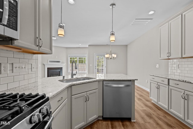 kitchen featuring tasteful backsplash, wood finished floors, stainless steel appliances, a sink, and a peninsula