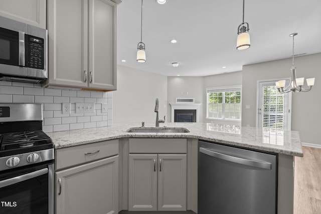 kitchen with tasteful backsplash, a sink, appliances with stainless steel finishes, wood finished floors, and a peninsula