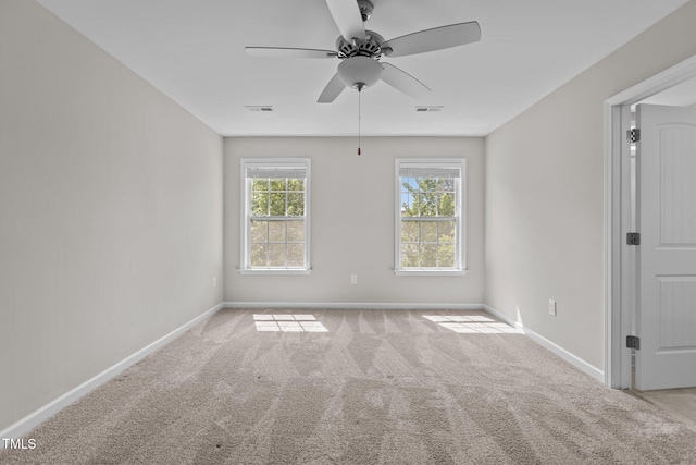 carpeted empty room featuring baseboards, visible vents, and a ceiling fan