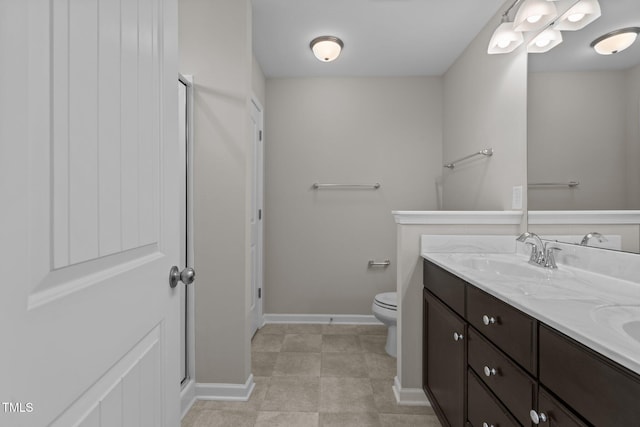 full bath featuring double vanity, an enclosed shower, toilet, a sink, and baseboards
