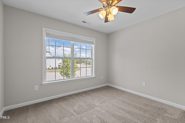 carpeted spare room featuring a wealth of natural light, visible vents, and baseboards