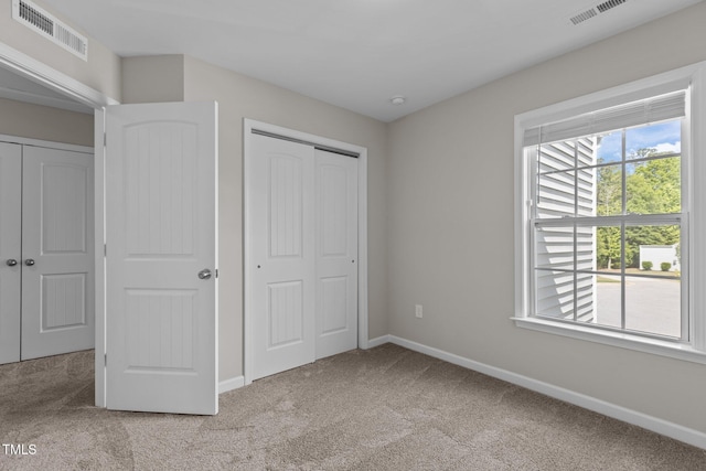 unfurnished bedroom with a closet, visible vents, carpet, and baseboards