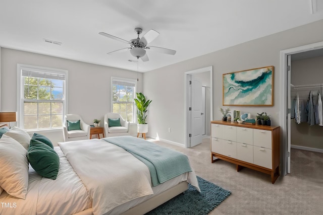bedroom with a ceiling fan, visible vents, baseboards, light colored carpet, and a spacious closet