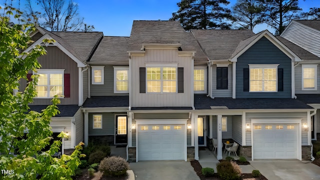 view of front of property with driveway, stone siding, an attached garage, and a shingled roof