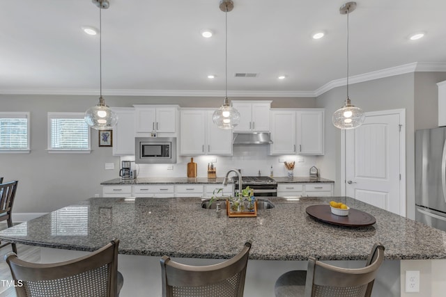 704 Haven Peak Ln, Wake Forest, NC 27587 - kitchen with under cabinet range hood, stainless steel appliances, a kitchen breakfast bar, white cabinetry, and an island with sink
