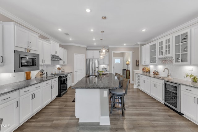 704 Haven Peak Ln, Wake Forest, NC 27587 - kitchen featuring appliances with stainless steel finishes, wine cooler, under cabinet range hood, a breakfast bar area, and tasteful backsplash