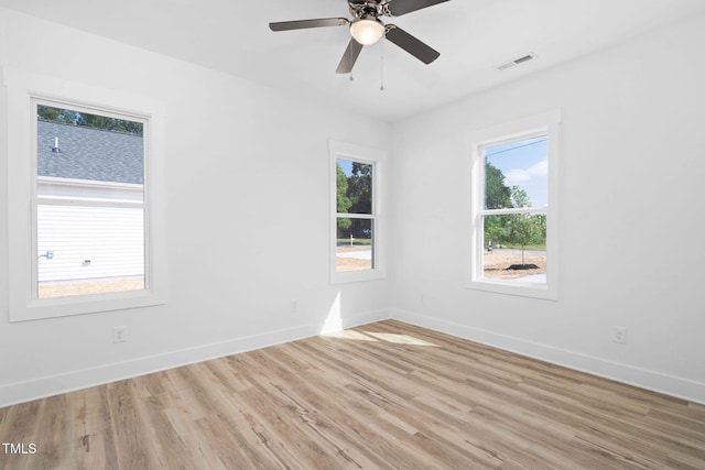 empty room with light wood-type flooring, baseboards, ceiling fan, and visible vents