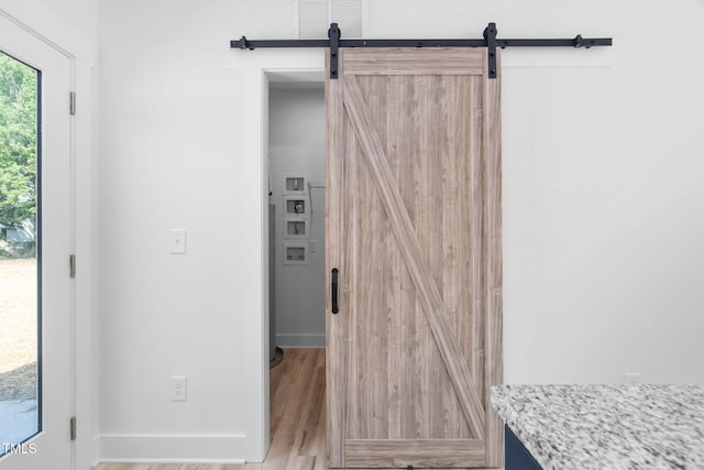 interior space with baseboards, wood finished floors, and a barn door