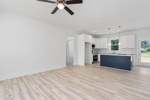 unfurnished living room featuring a sink, ceiling fan, light wood-style flooring, baseboards, and recessed lighting