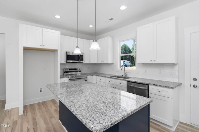kitchen with light stone counters, a sink, white cabinetry, and appliances with stainless steel finishes