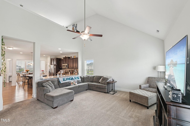 living room with visible vents, a ceiling fan, high vaulted ceiling, and light carpet