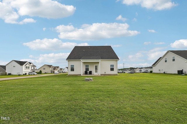 back of house featuring a fire pit, a residential view, and a yard