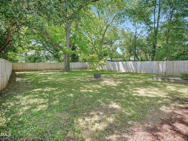 view of yard with a fenced backyard and a fire pit