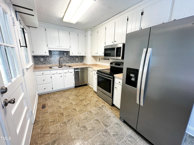 kitchen featuring a textured ceiling, visible vents, appliances with stainless steel finishes, a sink, and light countertops