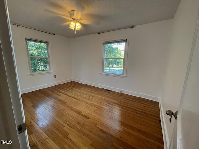unfurnished room featuring a healthy amount of sunlight, baseboards, hardwood / wood-style floors, and visible vents