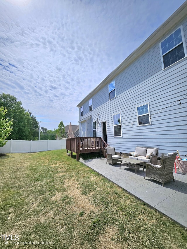 back of property featuring a lawn, a wooden deck, an outdoor living space, and a patio area