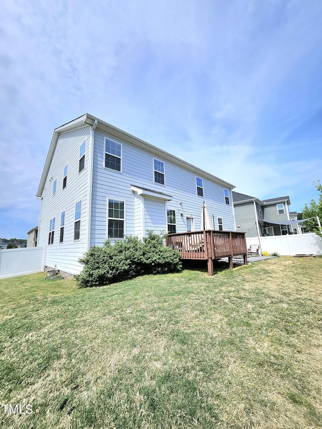 back of property with a lawn, a wooden deck, and fence
