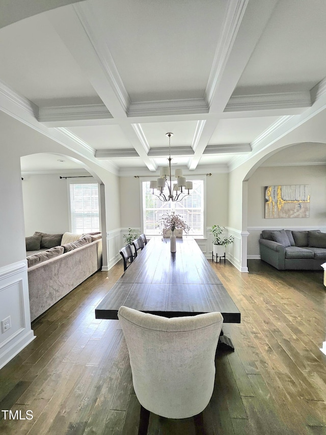 dining room featuring ornamental molding, arched walkways, beamed ceiling, and dark wood-style floors