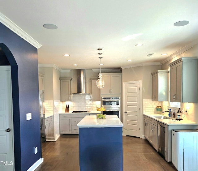 kitchen with tasteful backsplash, a sink, wall chimney exhaust hood, appliances with stainless steel finishes, and a kitchen island