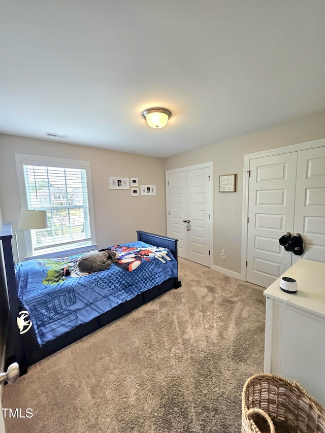 bedroom with two closets, visible vents, carpet flooring, and baseboards