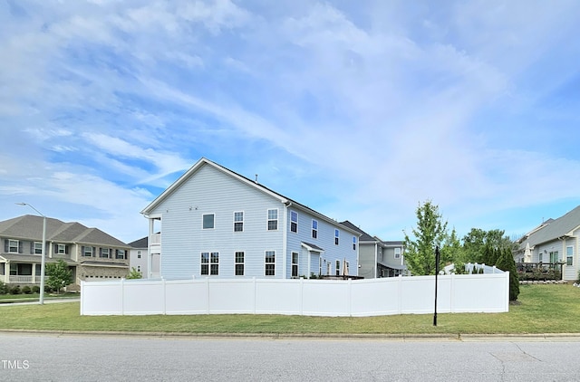 view of side of property featuring fence, a yard, and a residential view