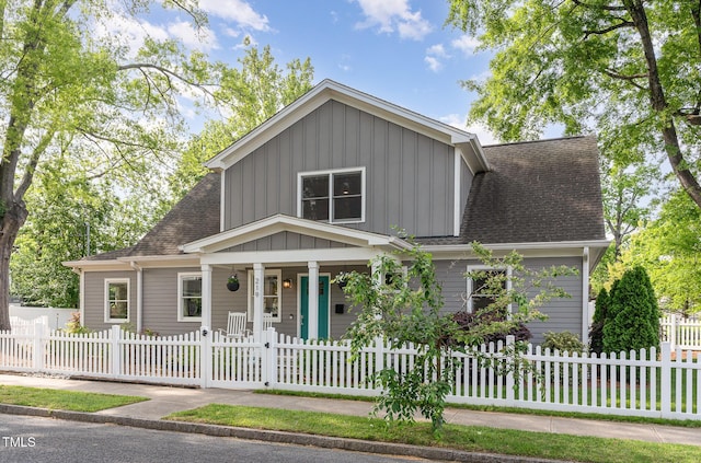 view of front of property with a porch, roof with shingles, board and batten siding, and a fenced front yard