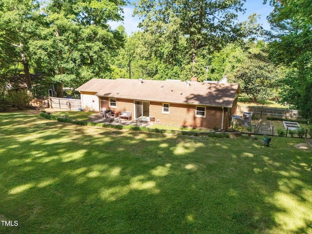 rear view of property with a lawn, a patio, fence, and brick siding