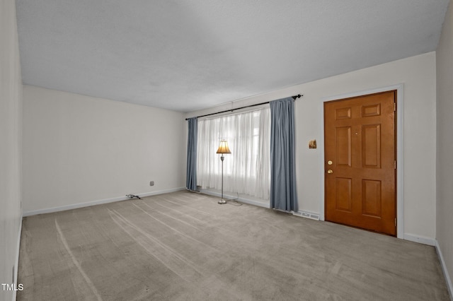 empty room with baseboards and light colored carpet