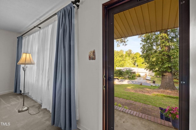 doorway to outside featuring carpet floors and baseboards