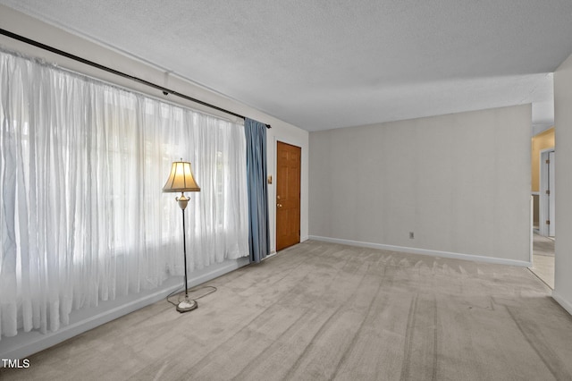 unfurnished living room with baseboards, a textured ceiling, and carpet