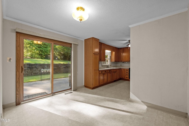 kitchen featuring brown cabinetry, light countertops, baseboards, a sink, and ornamental molding