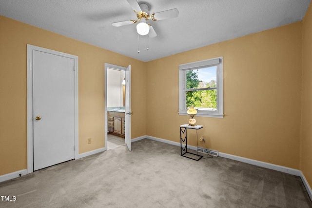 unfurnished bedroom with baseboards, ceiling fan, connected bathroom, and light colored carpet