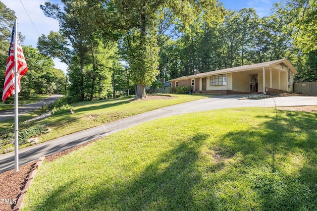 view of front of house with fence, an attached carport, concrete driveway, and a front yard