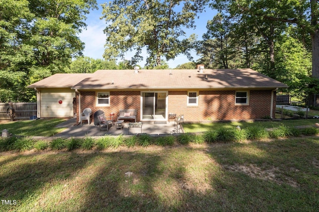 back of property with brick siding, a patio, fence, and a lawn